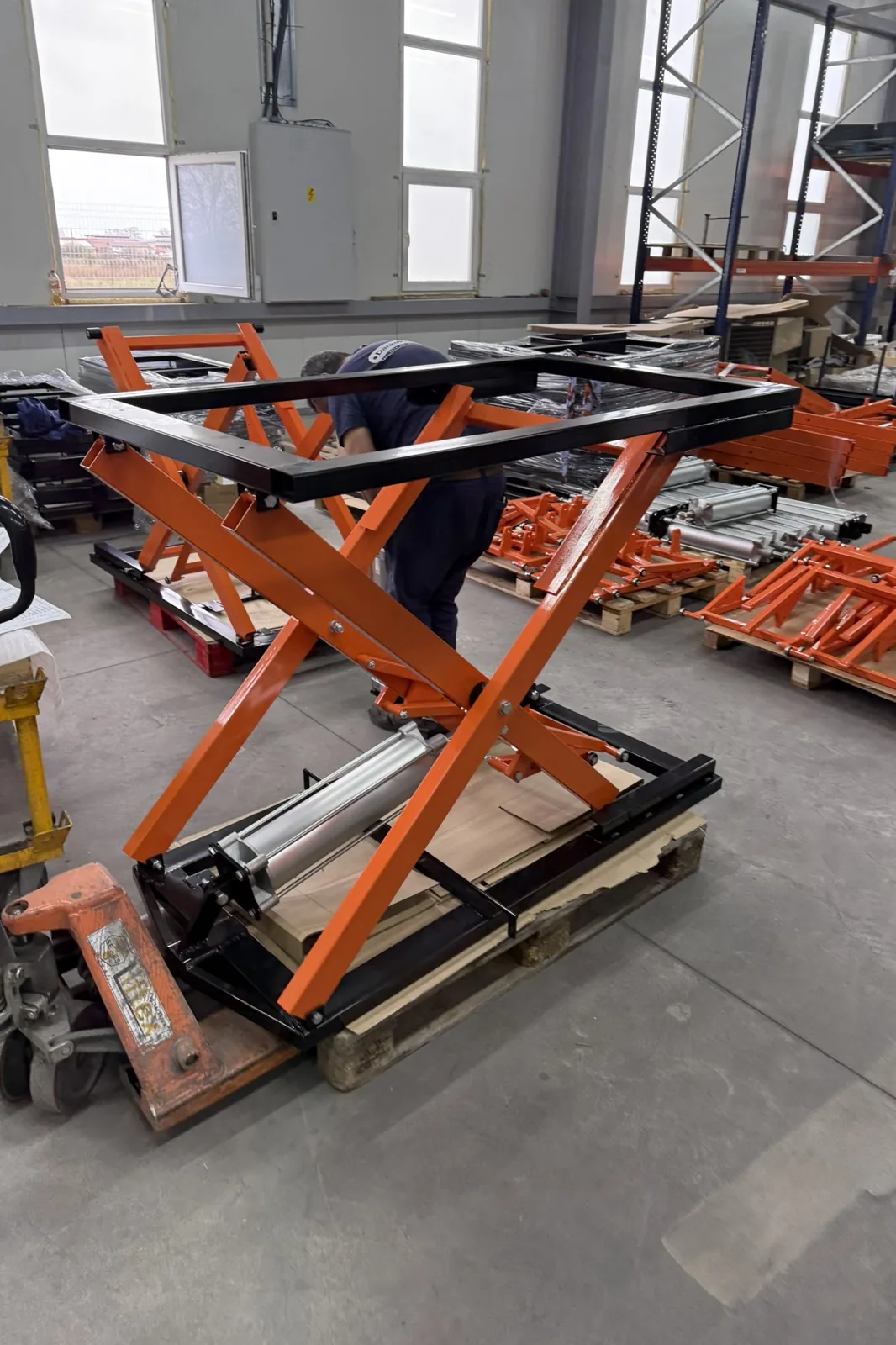 Scissor lift table on the assembly floor, with further units in production behind it