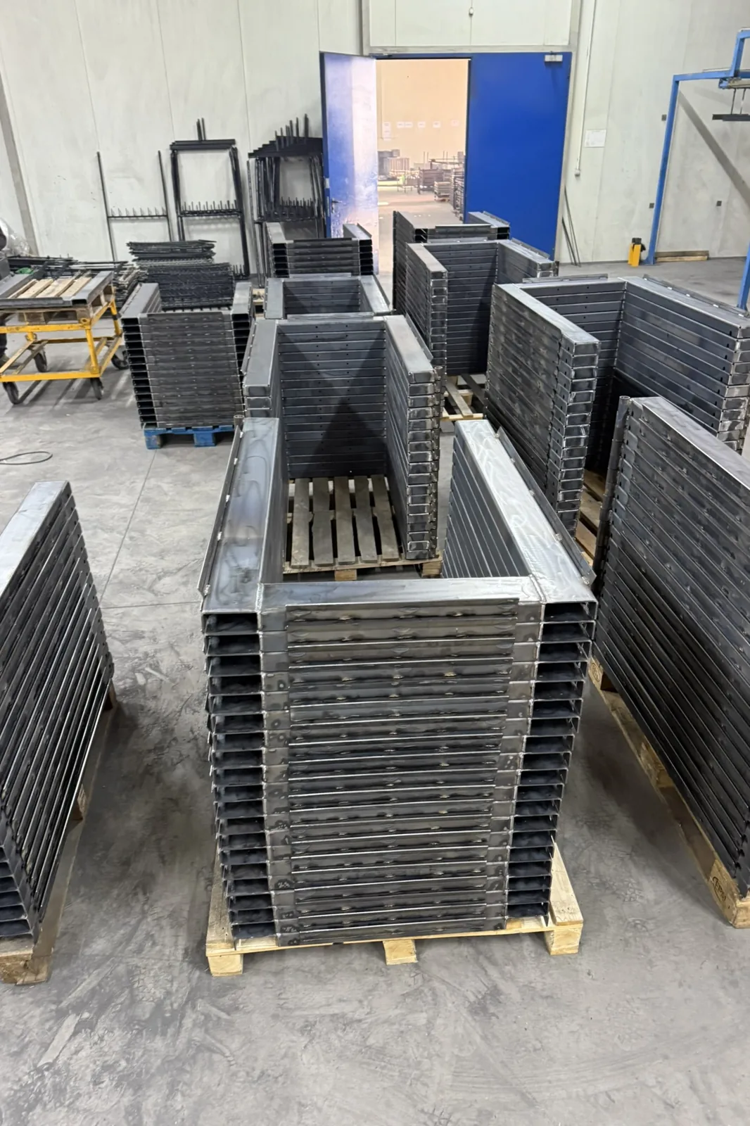 Stacked welded steel frames on pallets in the production hall